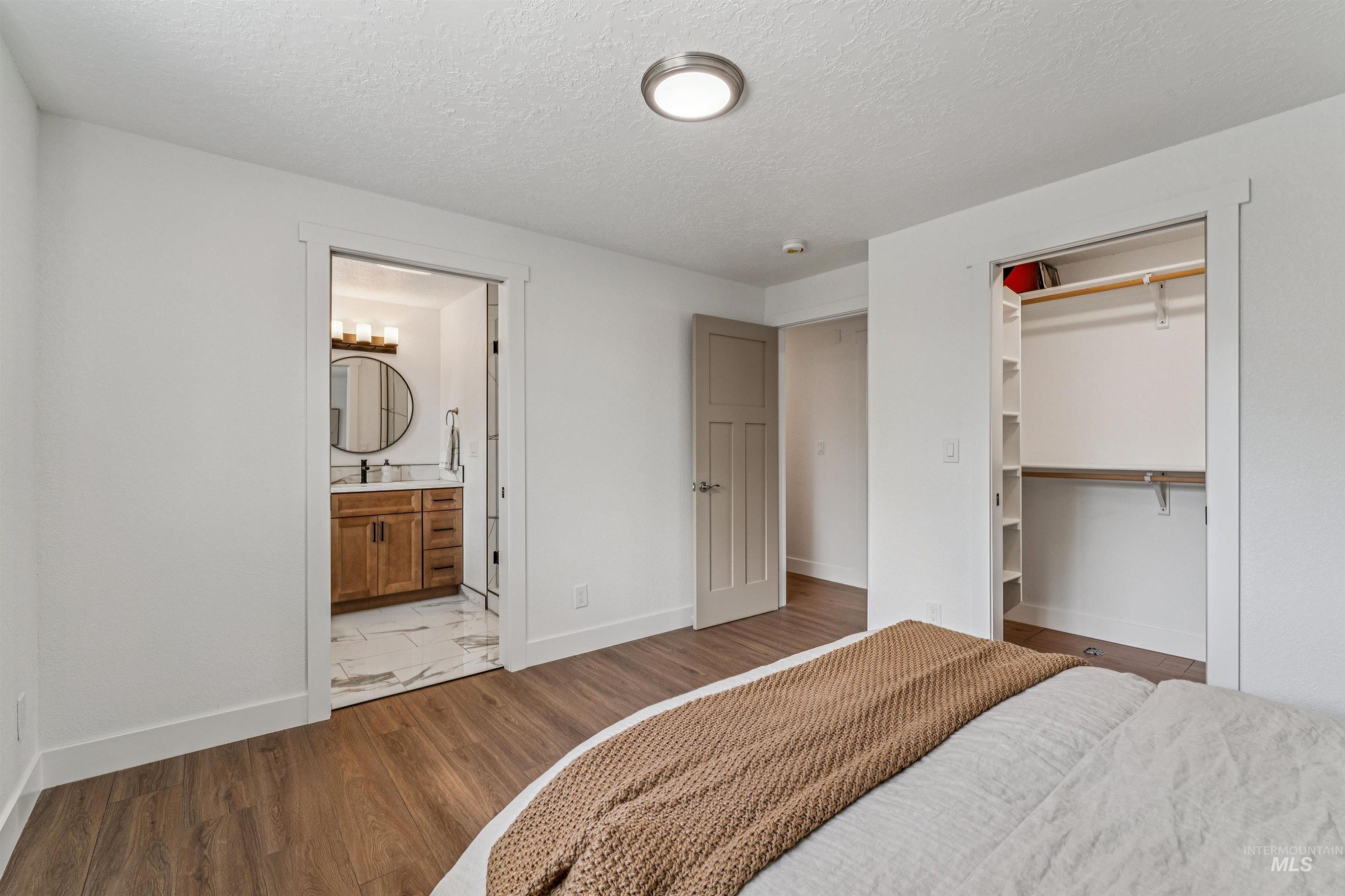 9709 West McMillan Road Boise, ID 83704 - Photo 25 of 50 Bedroom with dark wood-type flooring, a textured ceiling, a closet, and ensuite bathroom