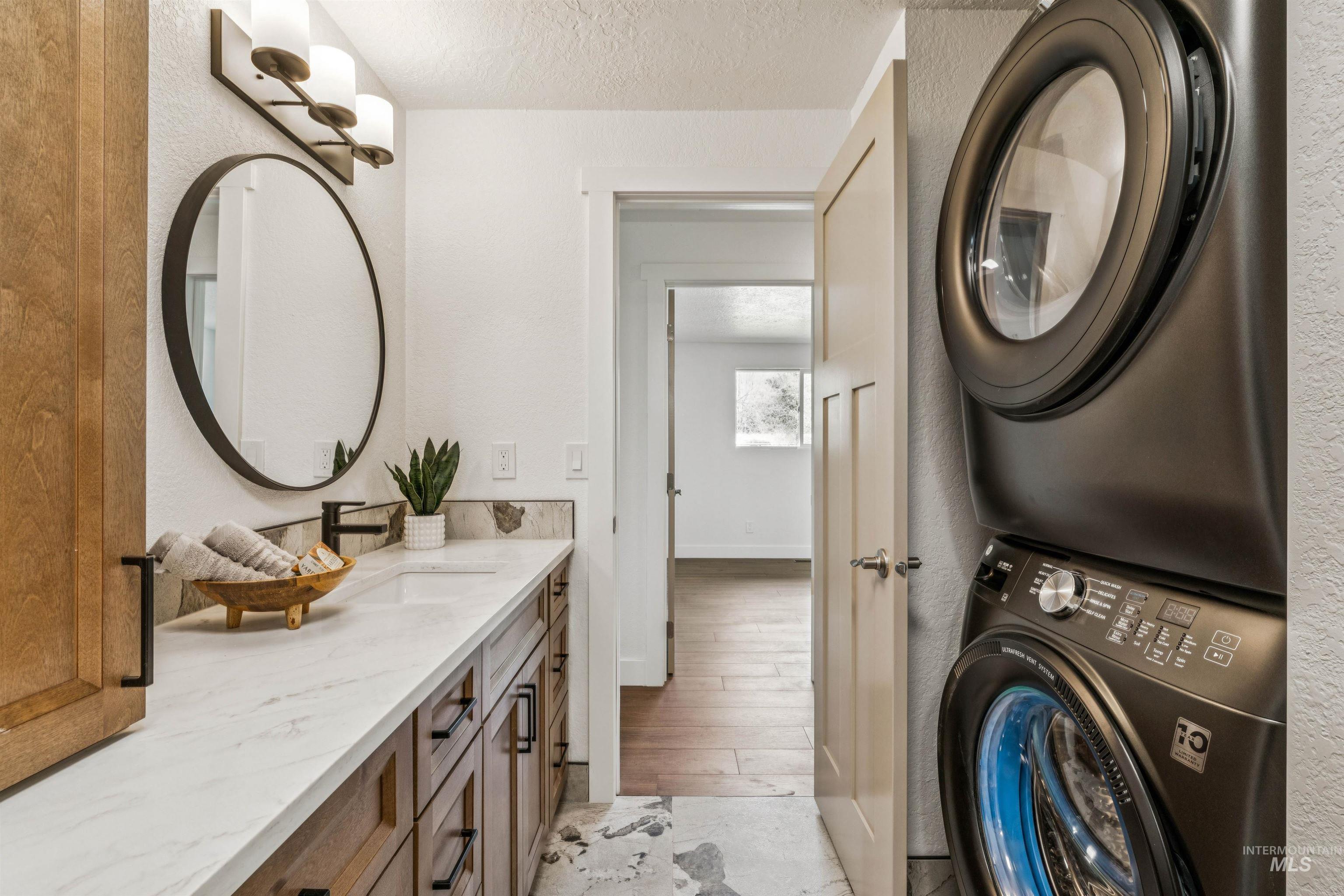 9709 West McMillan Road Boise, ID 83704 - Photo 31 of 50 Laundry area with a textured wall, stacked washer / drying machine, a textured ceiling, and light wood-type flooring