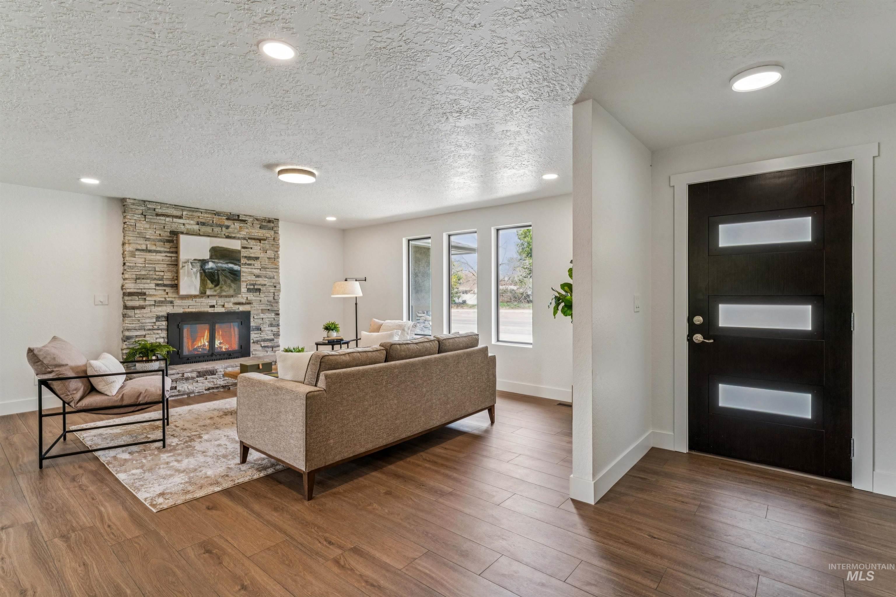 9709 West McMillan Road Boise, ID 83704 - Photo 6 of 50 Living area with a textured ceiling, wood finished floors, a stone fireplace, and recessed lighting