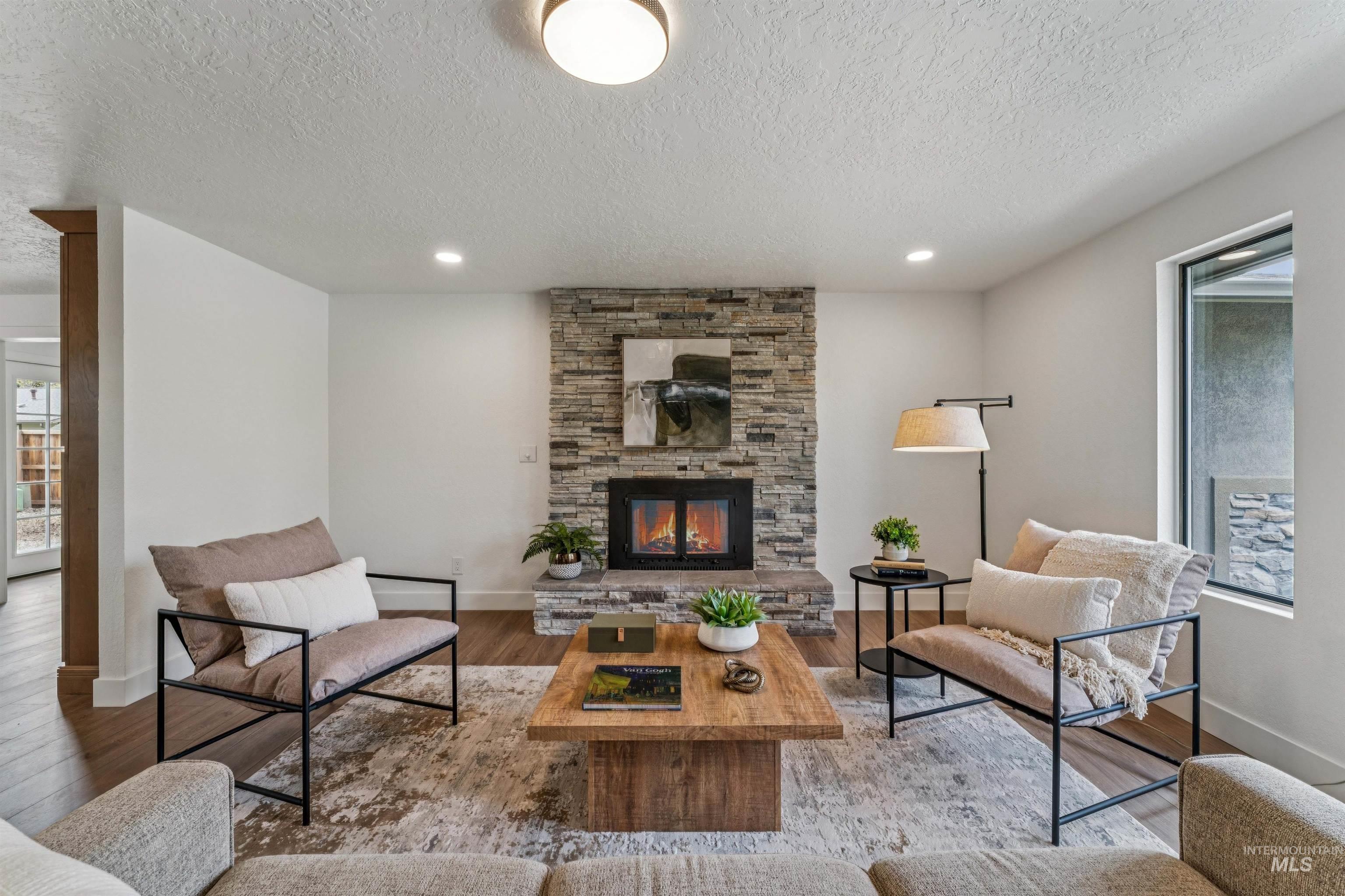 9709 West McMillan Road Boise, ID 83704 - Photo 9 of 50 Living area with a stone fireplace, wood finished floors, a textured ceiling, and recessed lighting