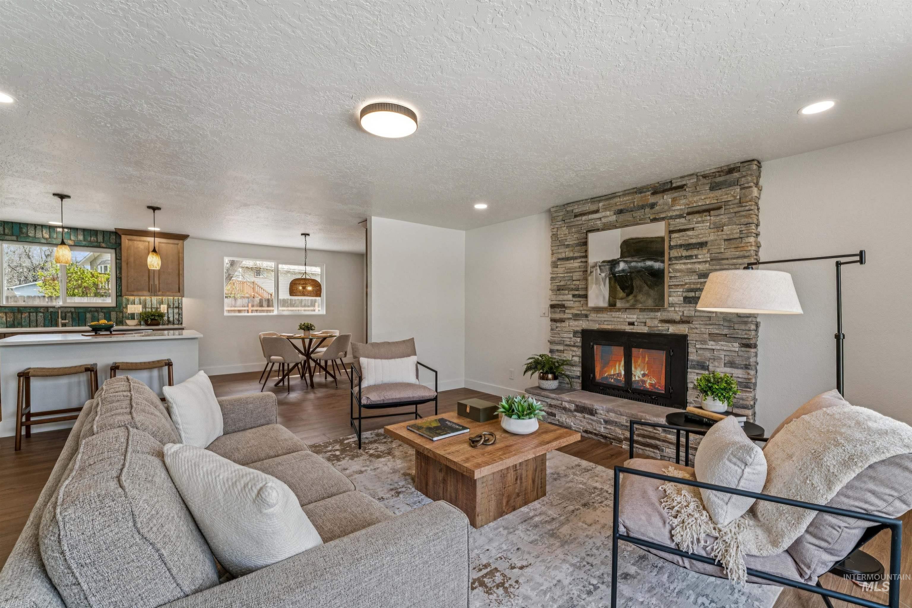 9709 West McMillan Road Boise, ID 83704 - Photo 10 of 50 Living area with a stone fireplace, wood finished floors, and a textured ceiling