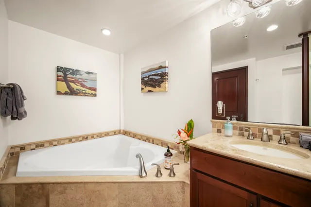 a bathroom with a tub a sink and mirror