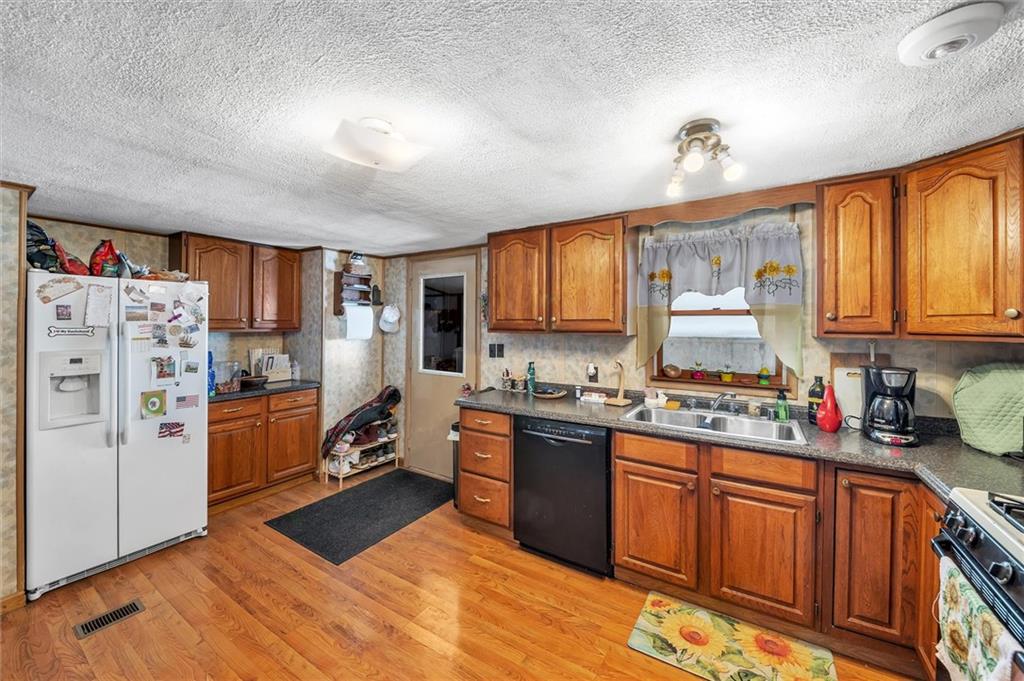 159 Sleepy Hollow Road Kittanning, PA 16201 - Photo 10 of 25 a kitchen with stainless steel appliances granite countertop a refrigerator a sink dishwasher a stove and white countertops with wooden floor