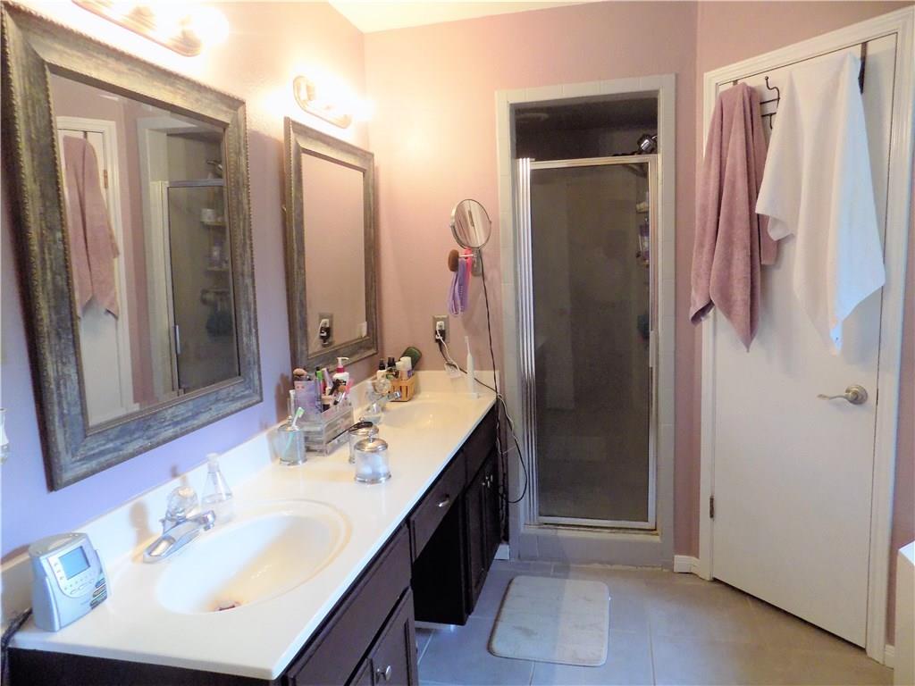 2306 Raintree Path Round Rock, TX 78664 - Photo 11 of 15 Bathroom featuring a double vanity with an integrated sink, white countertop, dark wood-finish cabinetry, and framed mirrors