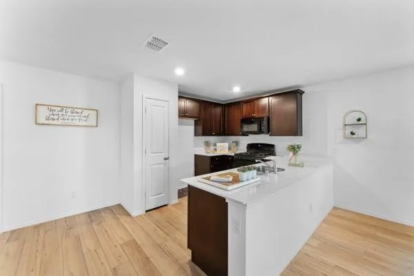 a large white kitchen with kitchen island a sink dishwasher a stove and a refrigerator with wooden floor