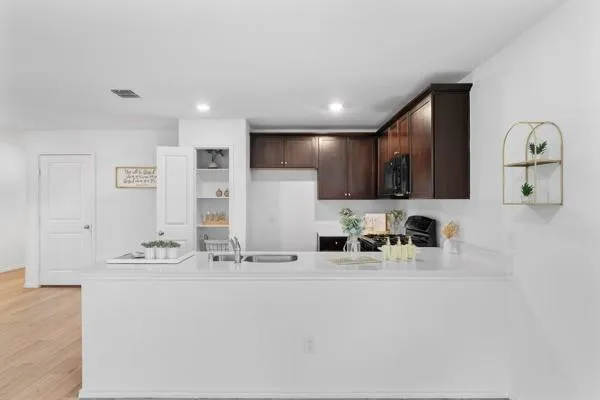 a kitchen with a refrigerator a stove top oven a sink dishwasher and white cabinets with wooden floor