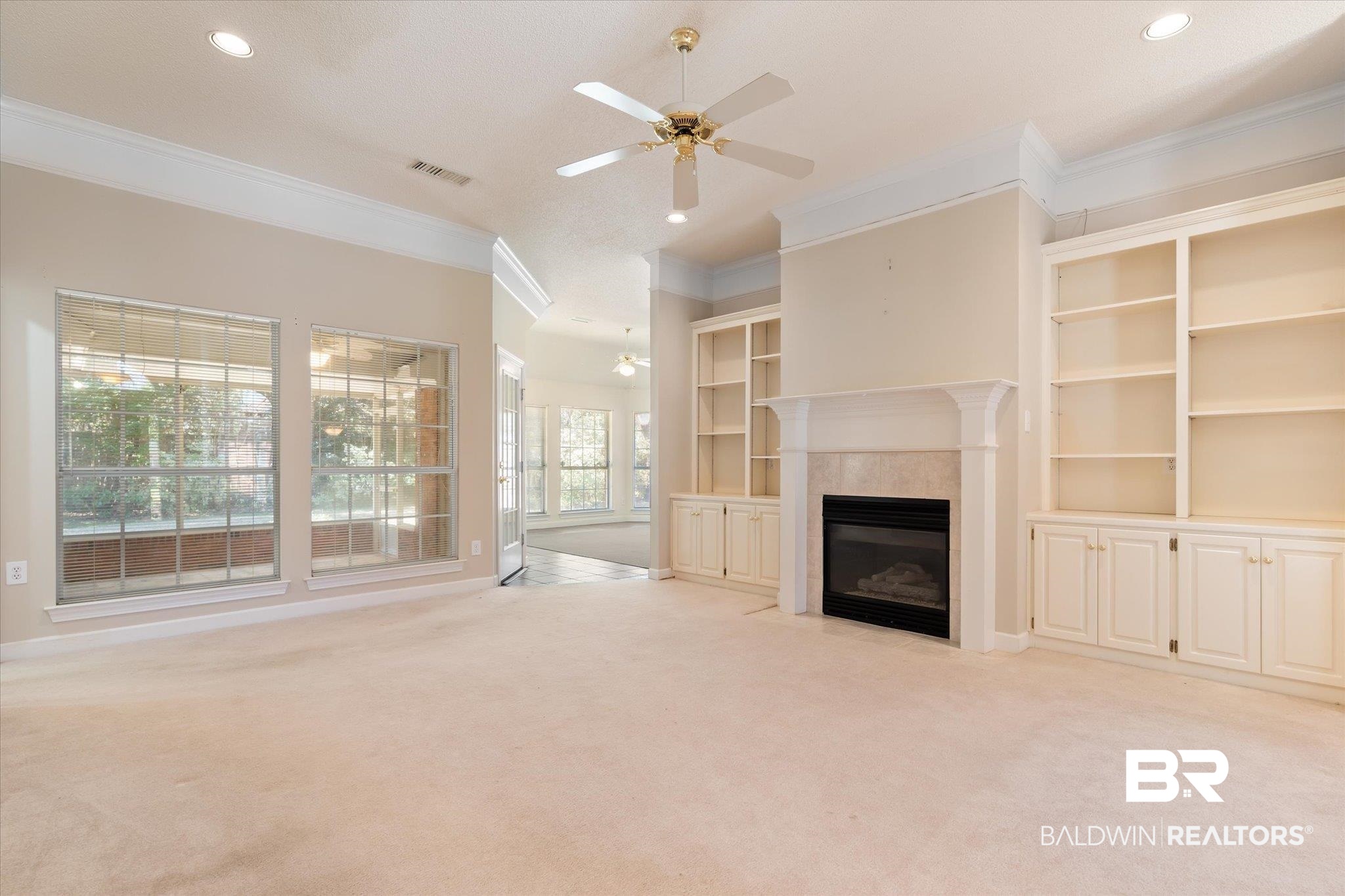 2220 Irongate Court Mobile, AL 36695 - Photo 2 of 20 Unfurnished living room featuring crown molding, visible vents, a fireplace, and light carpet