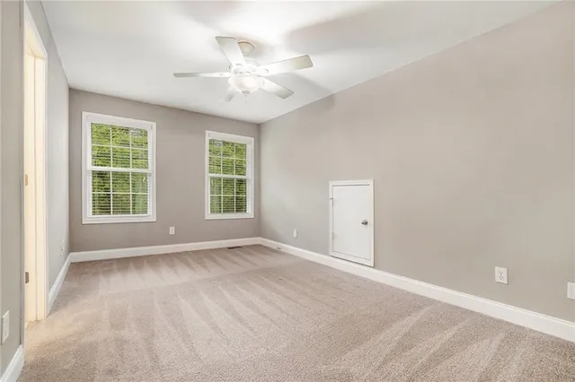 an empty room with chandelier fan and windows