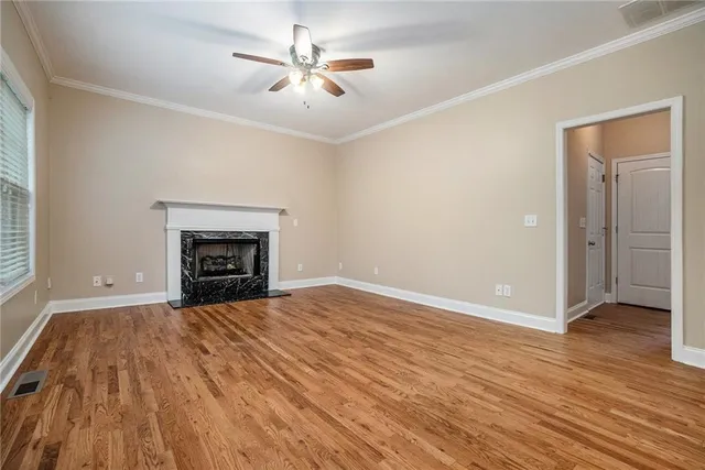 an empty room with wooden floor and ceiling fan
