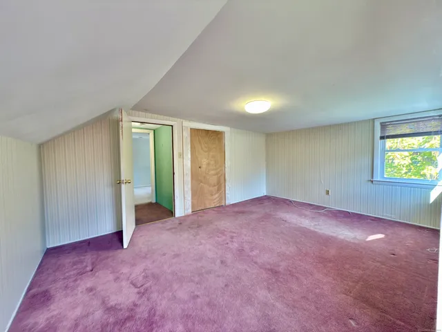 a view of an empty room with a window and a kitchen