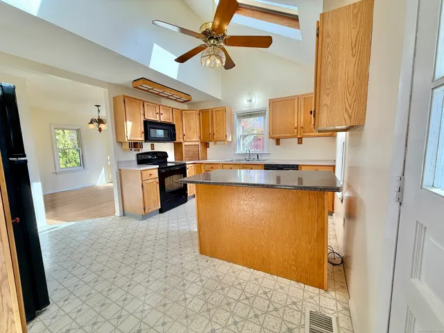 a kitchen with stainless steel appliances granite countertop a refrigerator a stove and a sink with wooden floor