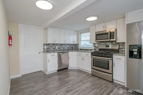 a kitchen with granite countertop a sink cabinets and stainless steel appliances