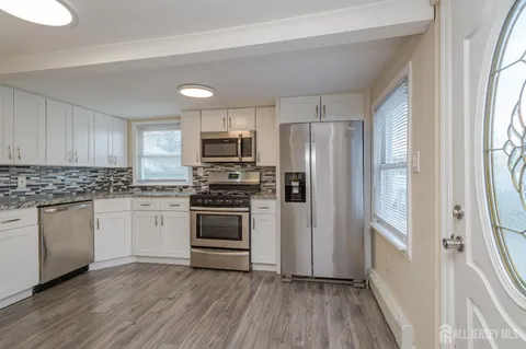 a kitchen with white cabinets stainless steel appliances a sink and a window