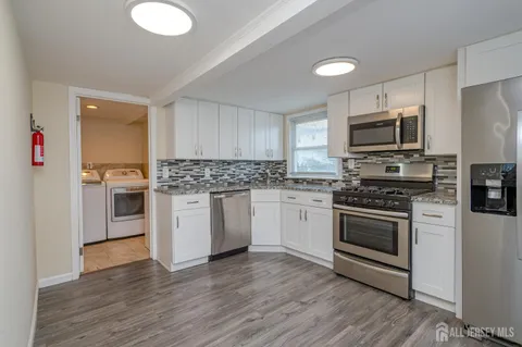 a kitchen with granite countertop a sink stainless steel appliances and cabinets