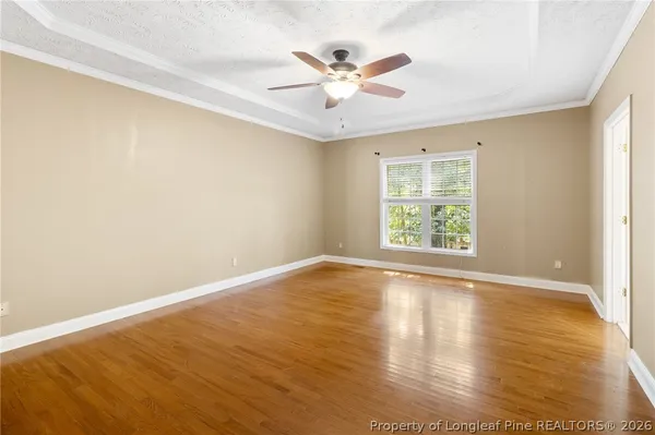 an view of an empty room with wooden floor and a window