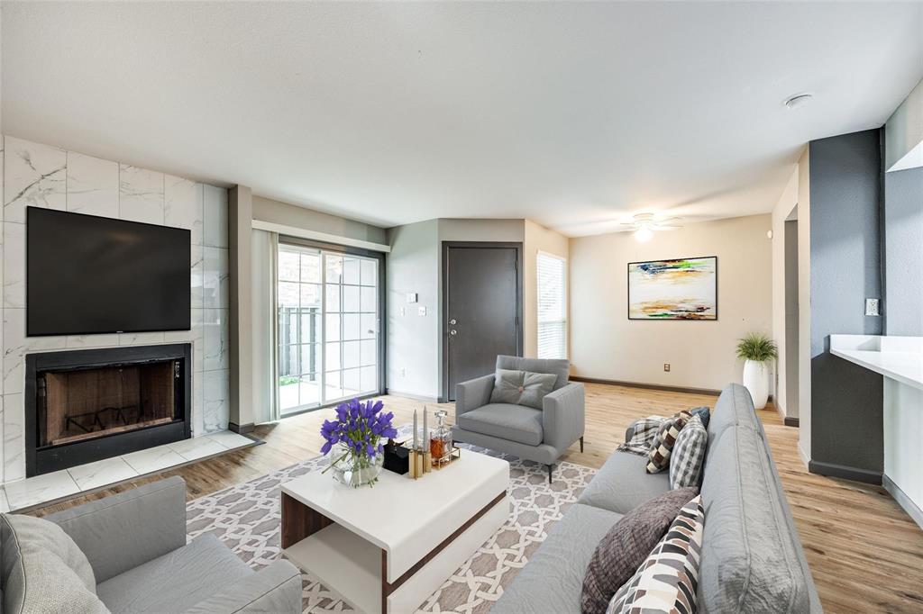 Living room featuring light wood finished floors, baseboards, a ceiling fan, and a premium fireplace