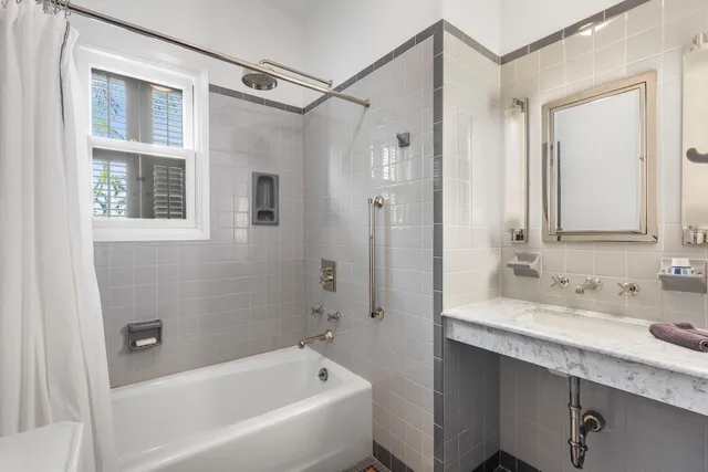 a bathroom with a bathtub shower sink vanity and mirror