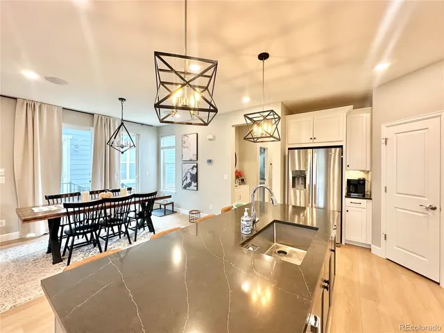 a dining room with stainless steel appliances kitchen island granite countertop a table chairs and a refrigerator