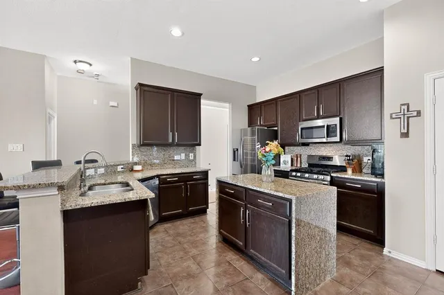 a kitchen with stainless steel appliances granite countertop a sink dishwasher stove and refrigerator
