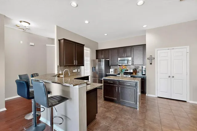 a kitchen with stainless steel appliances granite countertop a stove top oven a sink dishwasher a dining table and chairs