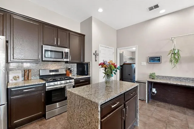 a kitchen with kitchen island granite countertop a sink and stove top oven