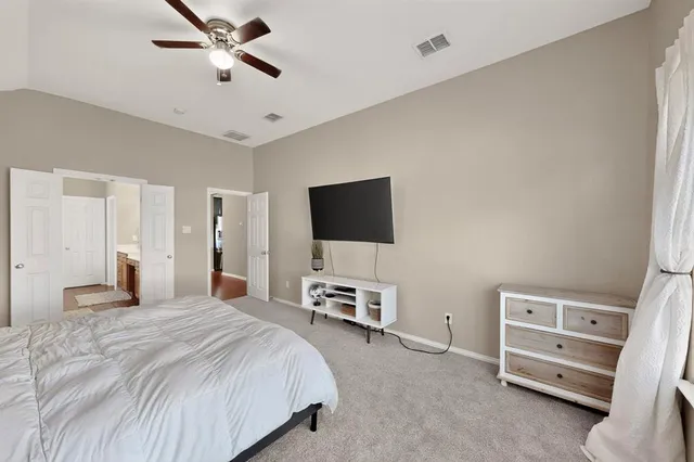 a bedroom with a bed and a flat tv screen on a dresser