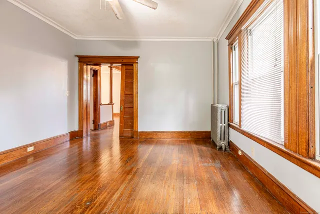 a view of an empty room with wooden floor and a window