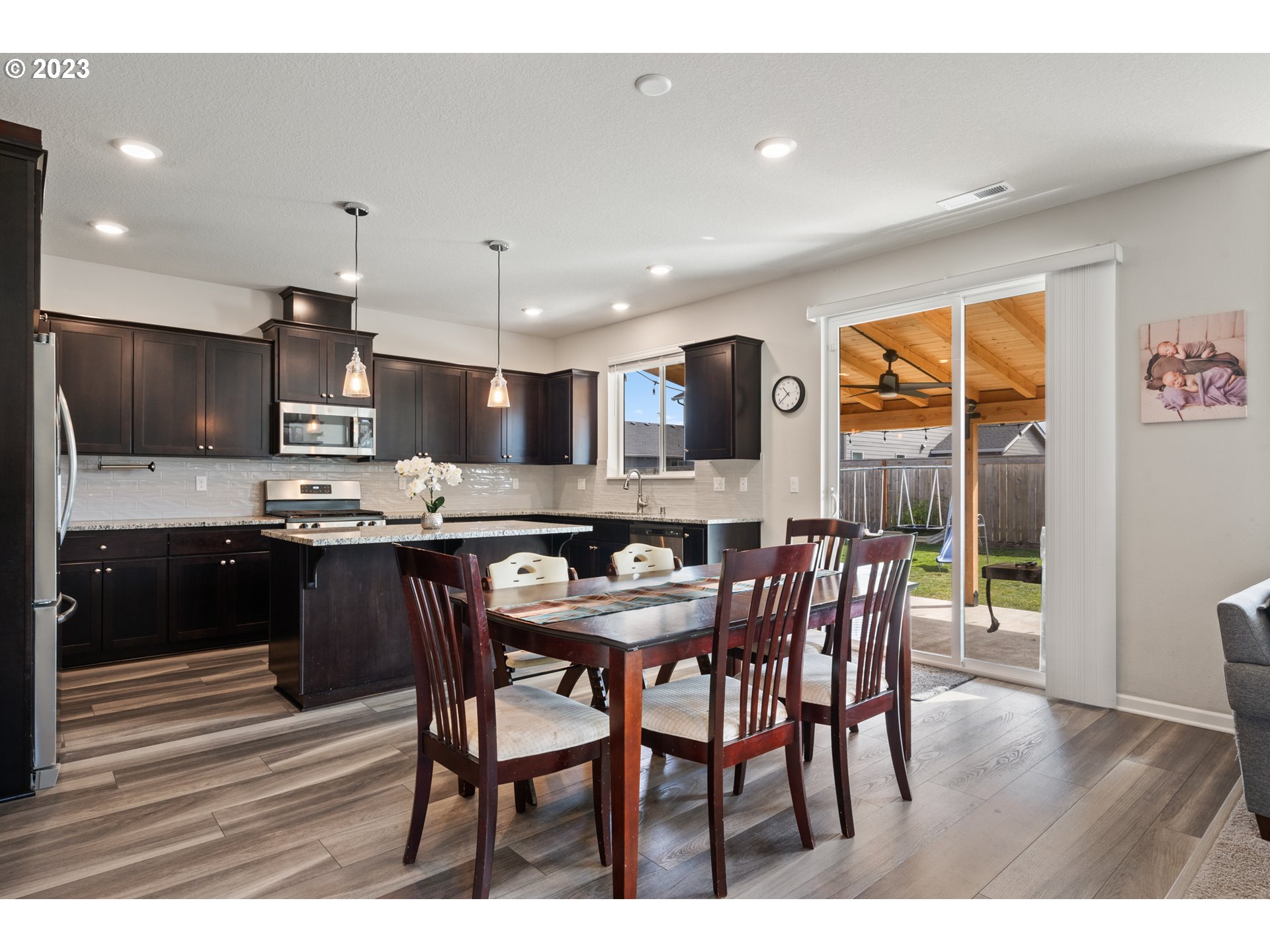 3912 South 41st Place Ridgefield, WA 98642 - Photo 4 of 20 a kitchen with stainless steel appliances kitchen island granite countertop a stove a refrigerator a sink a dining table and chairs with wooden floor