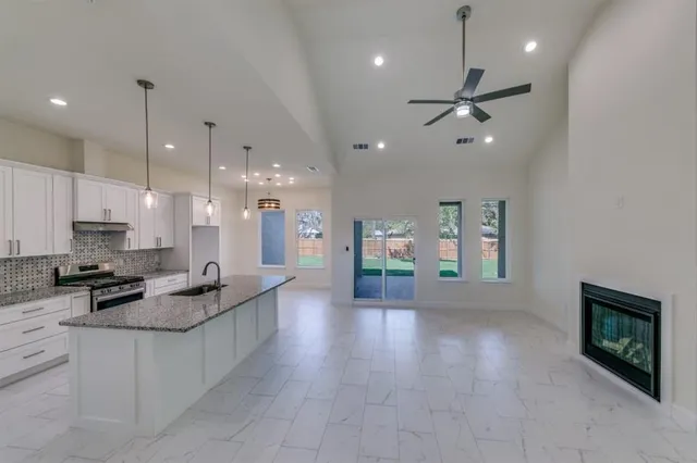 a open kitchen with granite countertop a stove top oven a sink a counter top space and living room view