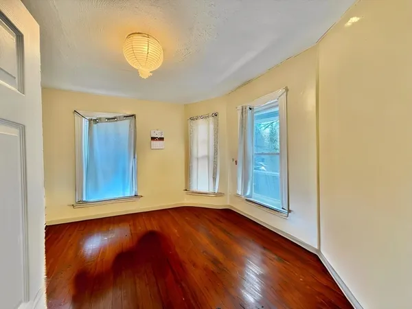 a view of a room with wooden floor mirror and window