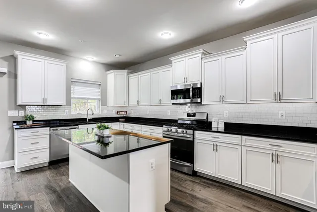 a kitchen with granite countertop white cabinets sink and stainless steel appliances