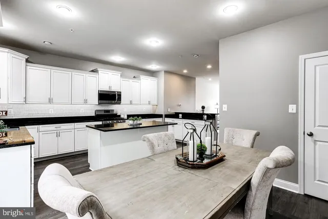 a kitchen with stainless steel appliances granite countertop a table and chairs in it