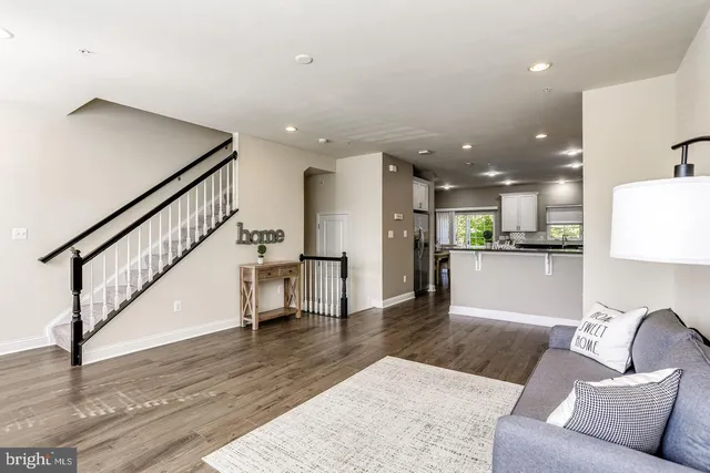 a living room with furniture and kitchen view with wooden floor
