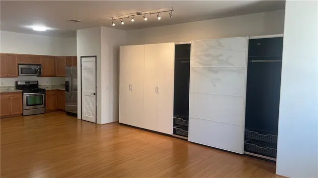 an empty room with wooden floor and a kitchen