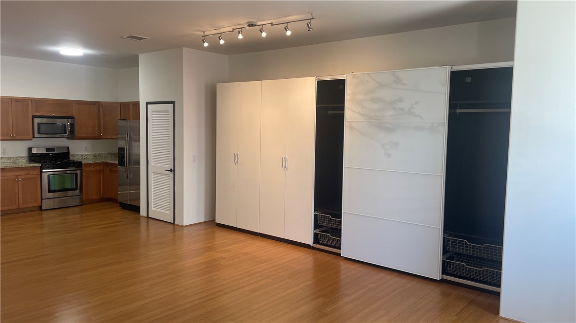 255 West 7th Street, Unit 13 San Pedro, CA 90731 - Photo 13 of 22 an empty room with wooden floor and a kitchen