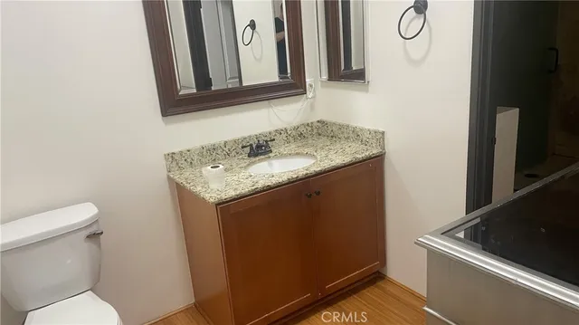 a bathroom with a granite countertop sink and a toilet