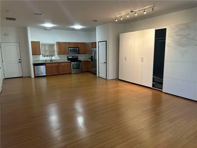an open kitchen with stainless steel appliances kitchen island wooden floors and granite counter top