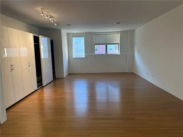 an empty room with wooden floor and windows