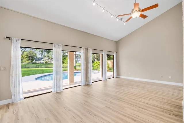 an empty room with wooden floor and windows