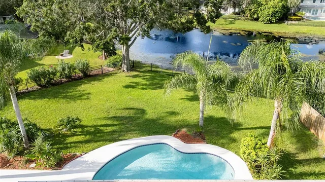 a view of swimming pool with a yard and large trees
