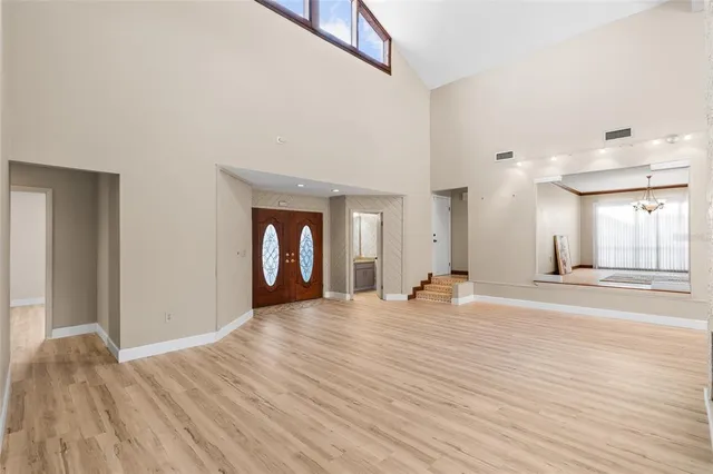 an empty room with wooden floor chandelier fan and windows