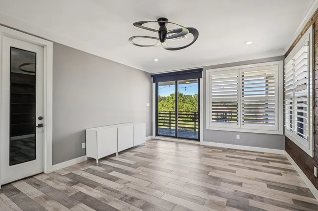 a view of an empty room with a window and wooden floor