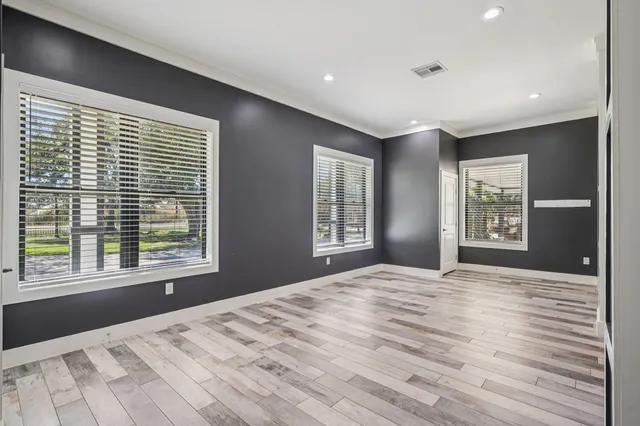 a view of an empty room with a window and wooden floor