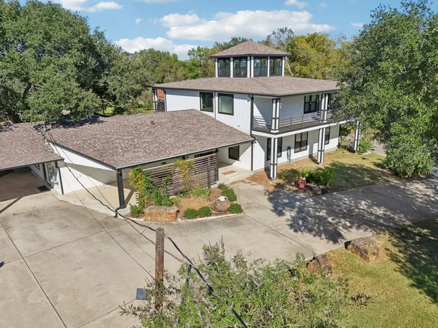 a aerial view of a house with yard and trees in the background