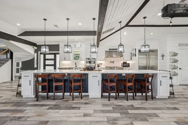a kitchen with stainless steel appliances granite countertop a table chairs sink and cabinets