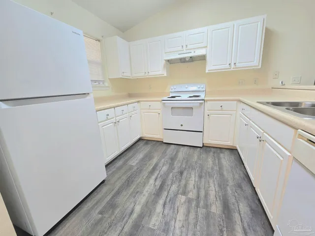 a kitchen with a sink a refrigerator and white cabinets