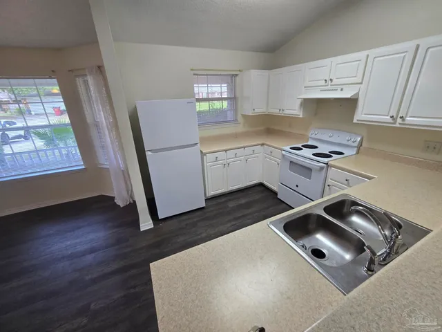 a kitchen with a stove a refrigerator sink and cabinets