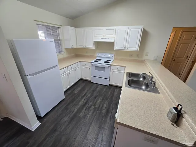 a kitchen with a refrigerator a white stove top oven and a sink