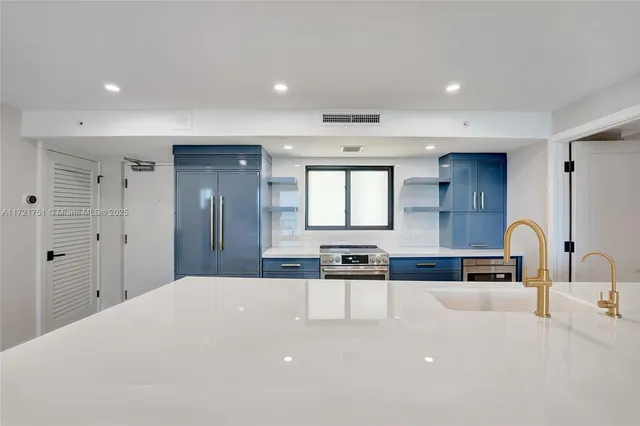 a kitchen with stainless steel appliances a sink a stove a refrigerator cabinets and a dining table