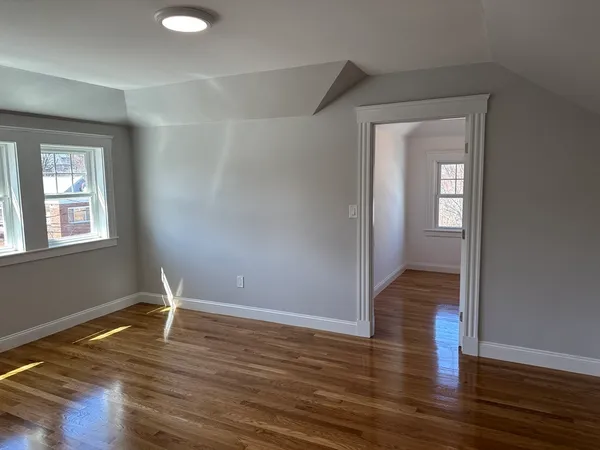 a view of an empty room with wooden floor and a window